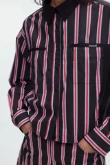 Camisa cropped de manga larga negra con estampado de lunares blancos, cuello camisero, cierre frontal de botones y bolsillos plaqué en el pecho.