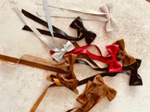 Moña de cuero color marrón con forma de lazo y tiras colgantes.