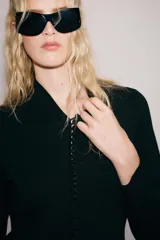 Chaqueta de punto negro con escote en V y manga larga. Cierre frontal con una hilera de pequeños botones forrados.