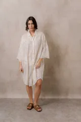 Camisola blanca de silueta amplia, manga larga y caída liviana, con bordados florales tono sobre tono, cuello camisero y cierre frontal con botones.