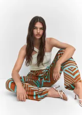 Pantalón de tiro medio con diseño recto y fluido, confeccionado en tejido satinado con estampado geométrico en tonos marrón y turquesa. Cuenta con cierre oculto de botón, gancho y cremallera, trabillas para cinturón, pinzas delanteras y dos bolsillos laterales.