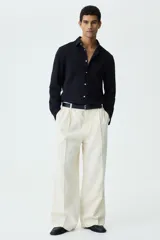 Camisa negra de punto elástico con cuello italiano, cierre frontal de botones y mangas largas.