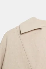 Blusa amplia confeccionada en mezcla de viscosa y lino, color beige, con cuello solapa, escote en V y manga larga.