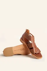 Sandalia de cuero color marrón chocolate, con suela plana y diseño calado con detalles trenzados.