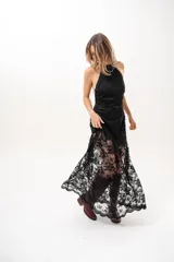 Vestido largo negro de encaje con cuello halter y espalda descubierta, con forro corto y falda translúcida.