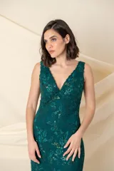 Vestido largo de fiesta en encaje color verde esmeralda, con escote en V, breteles anchos y falda con godets de tul. Presenta detalles de bordado con brillo en toda la prenda.