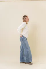 Jean wide leg de tiro alto con calce relajado y pierna amplia. Confeccionado en denim con leve desgaste, cuenta con cintura definida con presillas, bolsillos clásicos y cierre frontal con botón metálico.