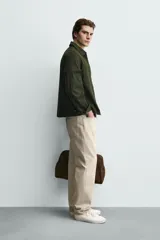 Sobrecamisa negra de corte relajado, confeccionada en tejido con mezcla de algodón elástico. Presenta cuello solapa, cierre frontal de cremallera, bolsillos de plastrón en el pecho y bolsillos de vivo en la cadera.