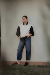 Chaleco de punto en color marrón oscuro, con cuello redondo y cierre frontal mediante botones metálicos decorativos con forma de sol.