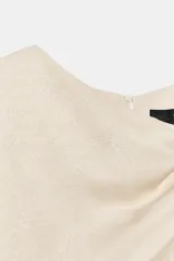 Vestido midi de escote asimétrico con una manga corta y un lado sin manga. Presenta un diseño drapeado en la parte delantera y cierre en la espalda con abertura y botones.