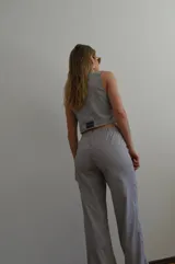 Chaleco a rayas verticales azules y blancas con cuello en V, cierre con botones y bolsillos frontales.