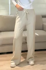 Palazzo de punto en color beige, con cintura elástica y cordón ajustable. Presenta un diseño de pierna ancha con costuras verticales decorativas en el frente.
