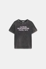 Camiseta de algodón con efecto lavado, cuello redondo y manga corta. Presenta un estampado frontal con texto en color claro.