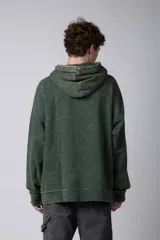 Buzo canguro de corte oversize en color verde con efecto de teñido desgastado. Cuenta con capucha, bolsillo frontal tipo canguro y puños acanalados.