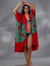 Capullo o kimono de paño 100% algodón, color rojo con estampado exclusivo en tono verde, de morfología amplia y envolvente, con bolsillos laterales y cinto independiente para ajustar la cintura.