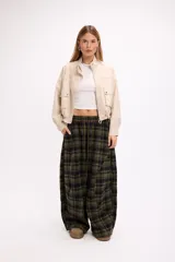 Pantalon de corte amplio y holgado con estampado de cuadros en tonos verde oliva y negro. Presenta cintura elástica con cordón ajustable y diseño de pierna ancha.