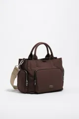 Bolso bandolera mediano Bimba y Lola de color marrón, con exterior de nylon, doble asa de mano y correa de tejido ajustable en tono tostado. Cuenta con bolsillos exteriores con cremallera, logo metálico de la marca en la parte frontal y herrajes plateados.