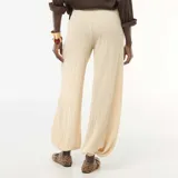 Pantalón de punto arrugado color beige, de tiro alto y corte amplio con botamanga ajustada.
