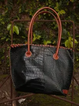 Bolso shopper de cuero azul con textura crocco, manijas largas marrones y costuras artesanales visibles en los bordes.