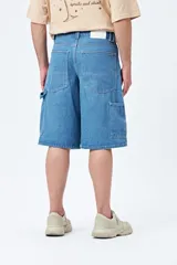 Bermuda de denim negro, estilo carpenter, con corte relajado y largo por encima de la rodilla. Presenta costuras visibles y múltiples bolsillos funcionales.