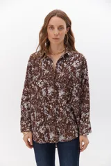 Camisa de corte holgado con estampado floral en tonos marrones y blancos, cuello clásico y cierre frontal con botones.