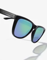 Lentes de sol unisex Hawkers modelo One Raw, con montura cuadrada negra y cristales polarizados color verde esmeralda.