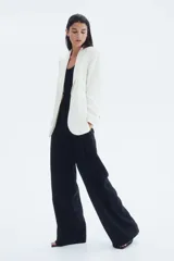 Blazer entallado color blanco con finas rayas verticales negras, solapas de pico, cierre de un botón, bolsillos delanteros de parche y puños con abertura y botón. Forrado.