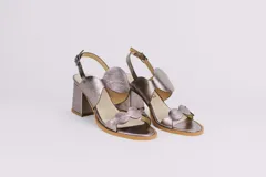 Sandalias doradas de cuero con taco cuadrado y diseño de ondas en el empeine y en la puntera. Cierre con hebilla en el tobillo.