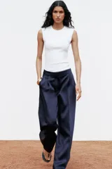 Top blanco de manga sisa con cuello redondo y corte ajustado al cuerpo.