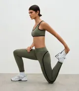 Legging deportivo de tiro alto en color verde oliva, con costuras laterales en contraste negro. Confeccionado en tejido de microfibra elástica, ofrece un ajuste ceñido y cómodo para actividades físicas.