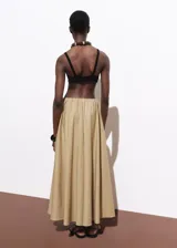 Falda larga de corte evasé en color beige, confeccionada en mezcla de algodón y poliamida. Presenta cintura con elástico, tiro bajo y bolsillos laterales.