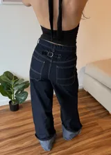 Pantalon de jean azul oscuro con costuras en contraste, corte wide leg y ruedo con doblez ancho en tono denim claro.