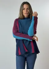 Sweater de punto grueso con cuello alto, diseño de bloques de color en azul marino, azul claro, fucsia y bordó. Presenta mangas largas y un corte holgado.