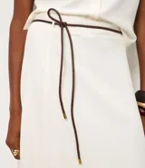 Pollera midi evasê color blanco, confeccionada en viscolino, con cintura alta y cinturón fino negro desmontable.