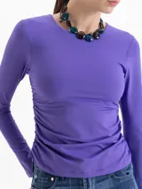 Top de lycra color violeta, con cuello redondo, mangas largas y detalle de frunces laterales en la cintura que aportan movimiento a la prenda.