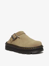 Mule Dr. Martens modelo Zebzag, color beige, confeccionado en gamuza. Presenta una correa ajustable con hebilla metálica, suela híbrida con cámara de aire en EVA y PVC, y las icónicas costuras amarillas de la marca.