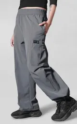 Pantalón de corte oversize confeccionado en microfibra técnica elastizada, color gris carbón. Presenta cintura elástica, bolsillos laterales, un bolsillo cargo con cierre de broche snap y sistema de elásticos con tancas en los tobillos para regular la apertura.