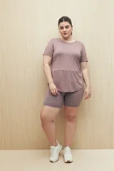 Remera deportiva color lila de manga corta con calce relajado y corte horizontal en la parte inferior.