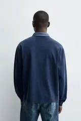 Sudadera polo azul marino de corte regular fit, con cuello solapa en contraste y cierre frontal de botonadura oculta. Tiene manga larga con puños acanalados y un efecto lavado.