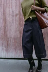 Bermuda de tiro alto en denim azul oscuro, corte ancho tipo culotte, con pinzas delanteras y pespuntes en color caramelo.