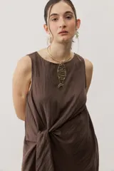 Vestido corto blanco sin mangas, con cuello redondo y detalle de nudo drapeado en el lateral.