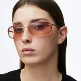 Lentes de sol con diseño envolvente de estilo Y2K, montura metálica dorada y cristales rectangulares con degradado en tonos marrones.