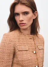 Chaqueta de tweed color tostado con cuello redondo, manga larga, cuatro bolsillos de parche con solapa en la parte delantera y cierre de botones con efecto joya. Presenta terminaciones deshilachadas y forro interior.