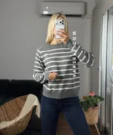 Sweater de punto con diseño de rayas horizontales negras sobre fondo blanco, cuello redondo y puños y ruedo acanalados.