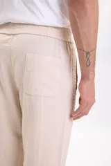 Pantalón casual de corte recto y diseño clásico, confeccionado con mezcla de lino en color beige, con bolsillos laterales y trabillas para cinturón.