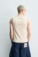 Camiseta sin mangas slim fit color crema, confeccionada en tejido de algodón elástico, con cuello redondo y ribetes en contraste color beige.