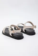 Sandalia baja negra con doble tira en el empeine tejida en beige y negro, tira de agarre en el tobillo con hebilla y plataforma de 3 cm de alto.