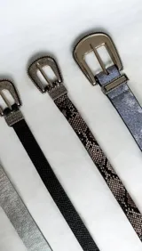 Cinto de cuero sintético con estampado de piel de serpiente y hebilla metálica plateada con detalles grabados de estilo western.