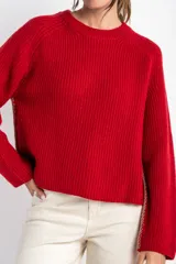 Sweater de lana color rojo, con cuello redondo, mangas largas y detalle de costura decorativa en los laterales.