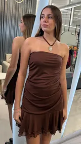 Vestido corto color chocolate, con diseño strapless y detalle de fruncido lateral. Presenta un ruedo con volado de tul que aporta volumen y movimiento.